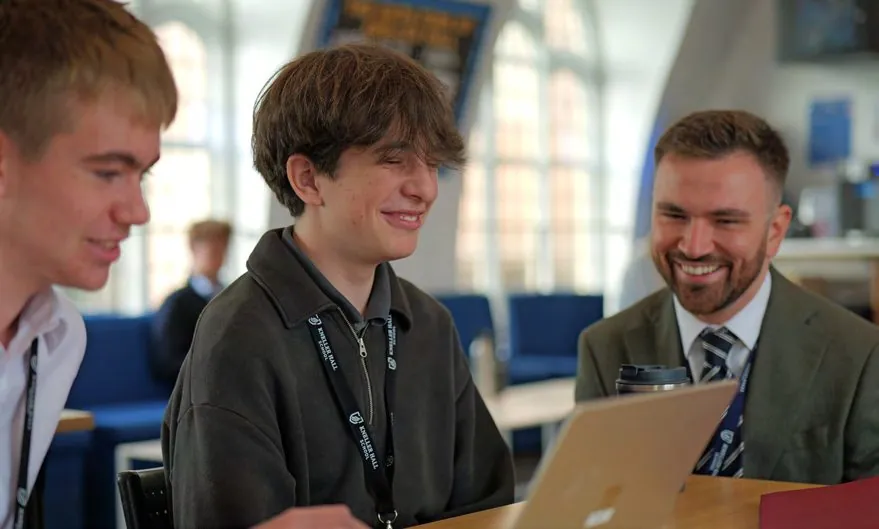 Pupils and a teacher smiling together over a laptop